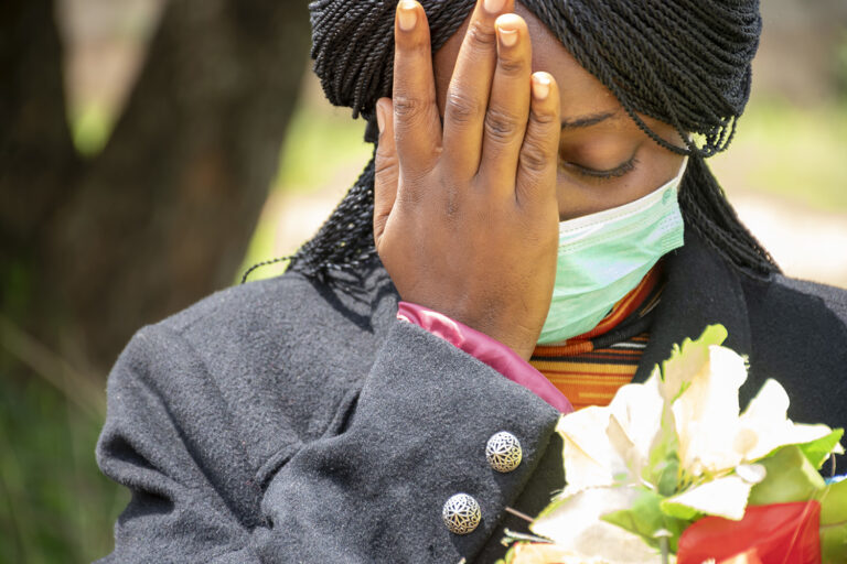 shallow focus shot of a young nigerian woman mourning while holding flowers