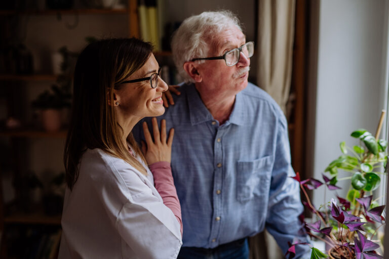 healthcare worker or caregiver visiting senior man indoors at home, talking.